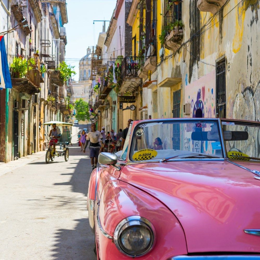 A vintage convertible on a sunlit colonial street.