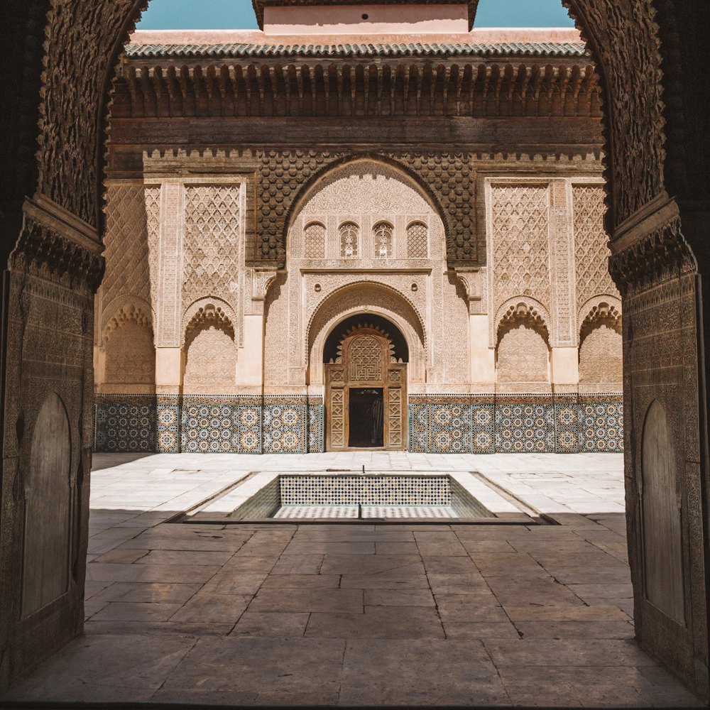 A carved courtyard and reflecting pool seen through an arch.