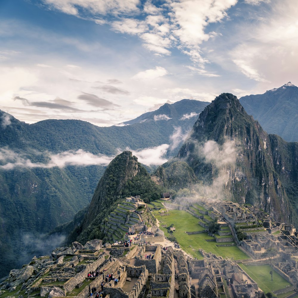 Terraced ruins on a ridge among cloud-covered peaks.
